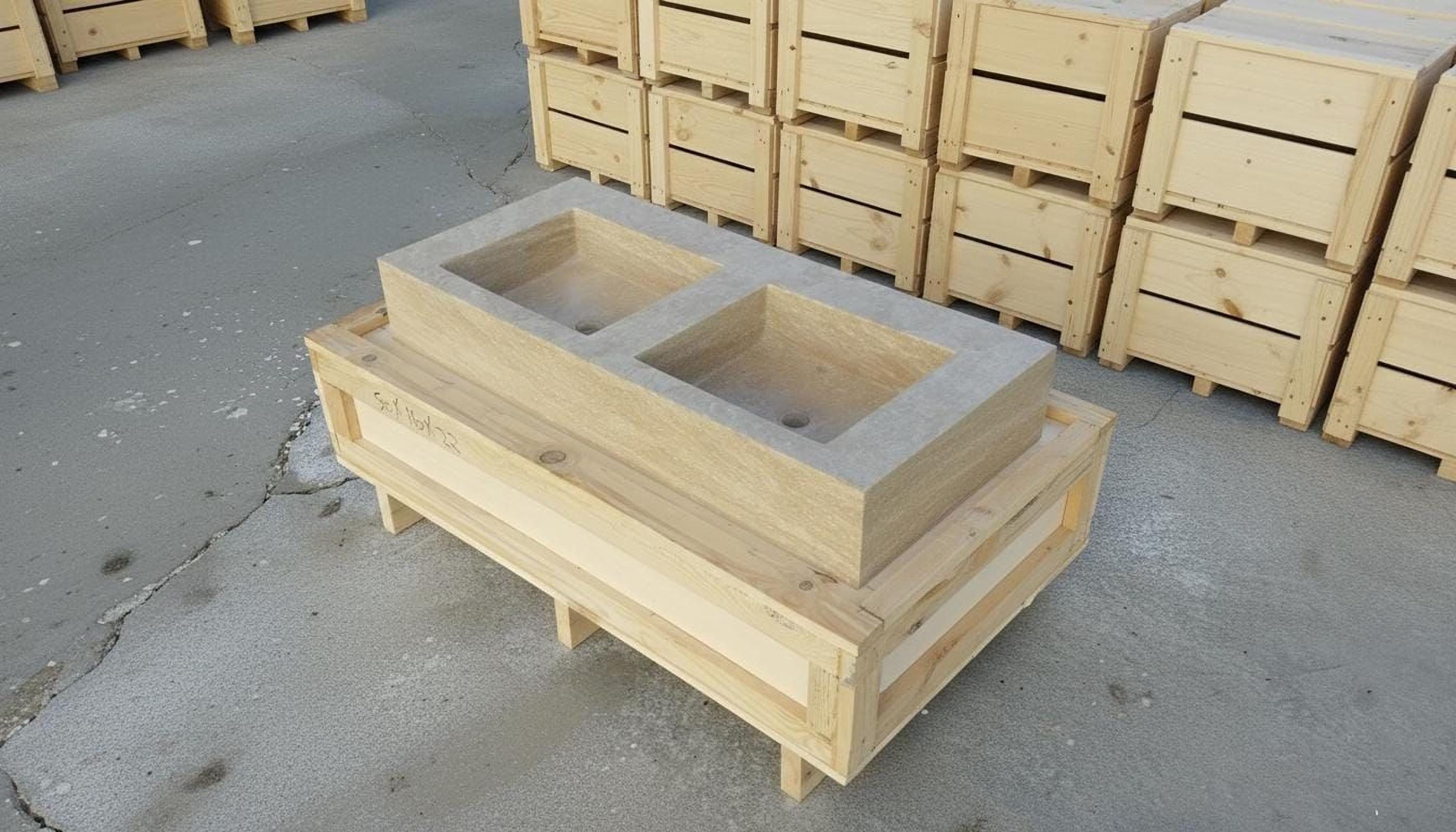 a wooden structure with two square basins, likely intended for use in a bathroom or other similar setting. The structure is placed on a wooden pallet, and there are several wooden crates stacked nearby.